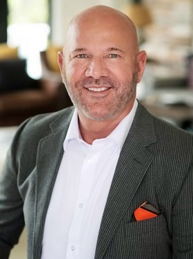 A man in a suit and tie smiling for the camera.